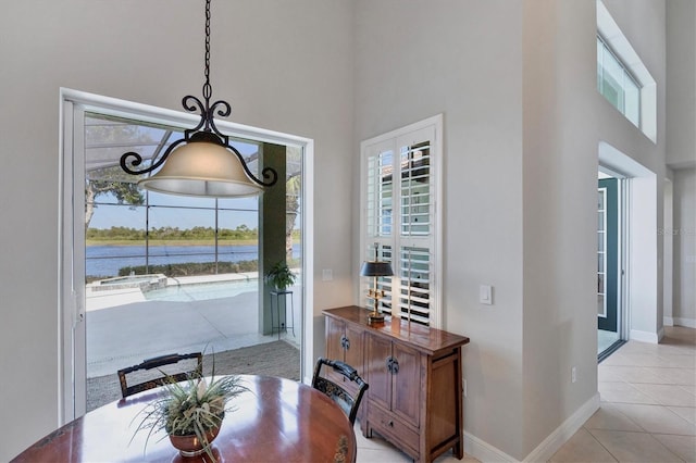 dining room with a water view, plenty of natural light, a high ceiling, and light tile patterned floors