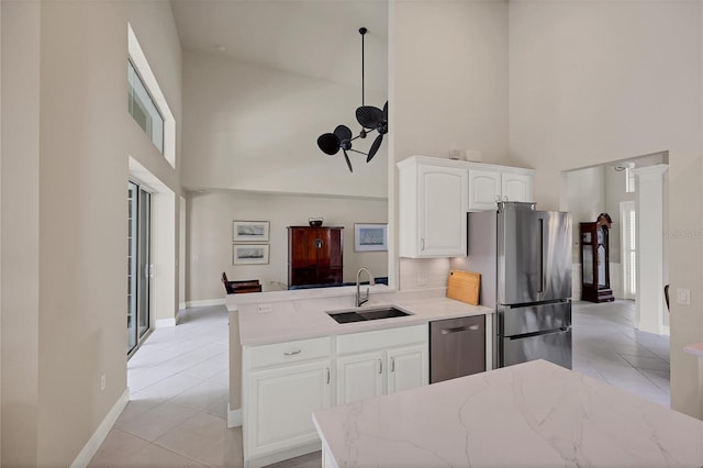 kitchen featuring appliances with stainless steel finishes, a towering ceiling, light tile patterned floors, and white cabinets