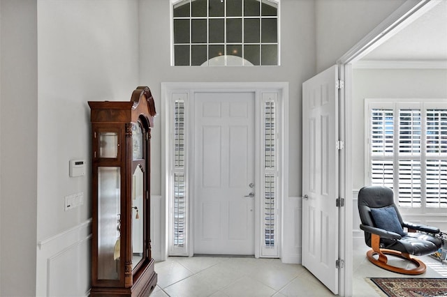 tiled foyer with ornamental molding and a high ceiling