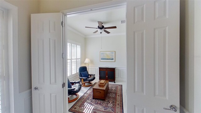 living area with crown molding and ceiling fan