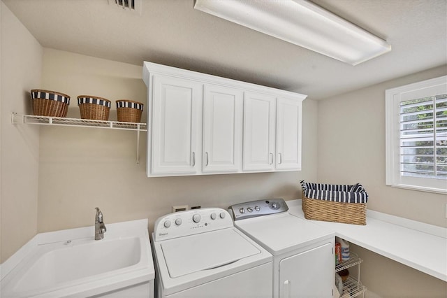 washroom featuring washing machine and dryer, cabinets, and sink