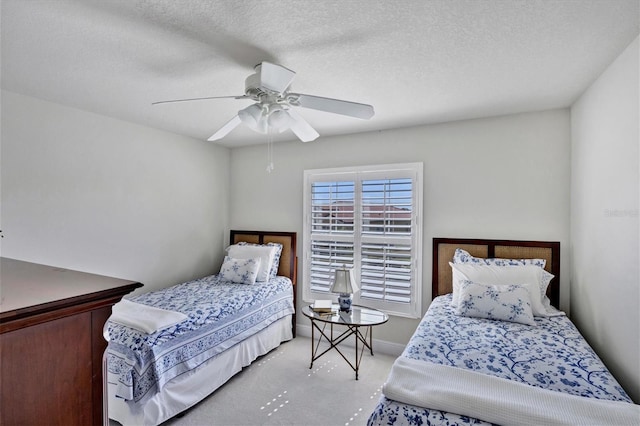 bedroom featuring a textured ceiling, ceiling fan, and light colored carpet