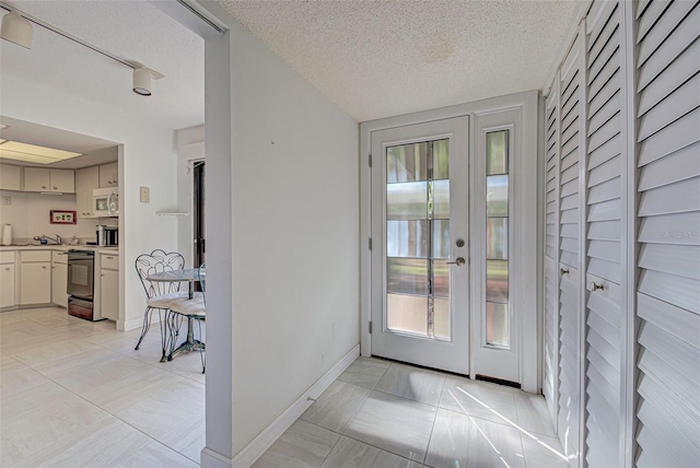 doorway to outside with a textured ceiling and light tile patterned floors