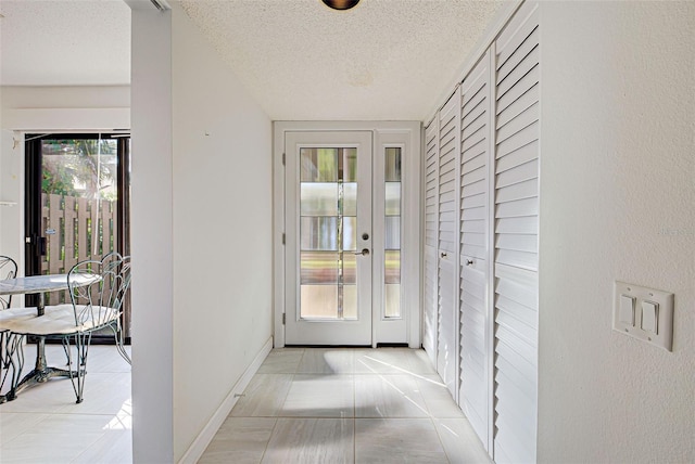 entryway with a textured ceiling and light tile patterned flooring