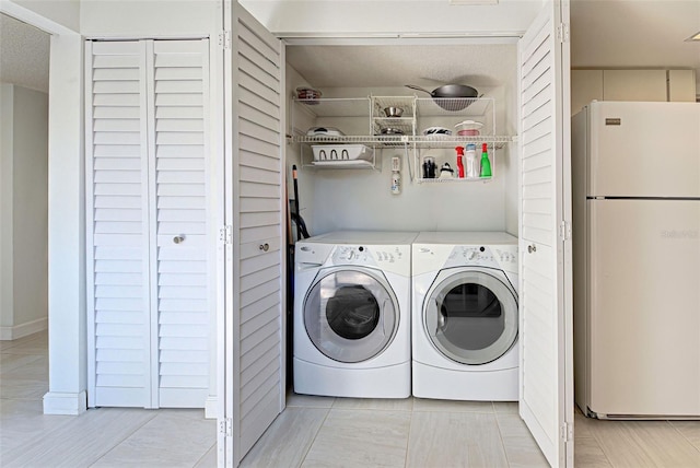 washroom with a textured ceiling, light tile patterned floors, and washer and dryer