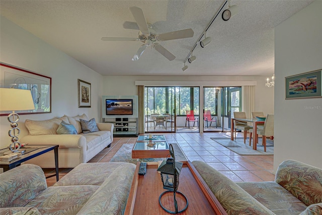 living room featuring rail lighting, a textured ceiling, ceiling fan with notable chandelier, and light tile patterned flooring