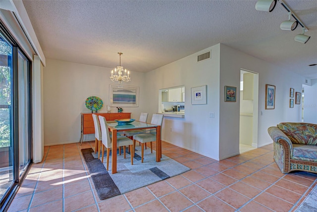 dining area featuring a textured ceiling, light tile patterned floors, track lighting, and plenty of natural light