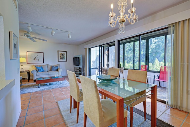 dining area with ceiling fan with notable chandelier, a textured ceiling, and tile patterned floors