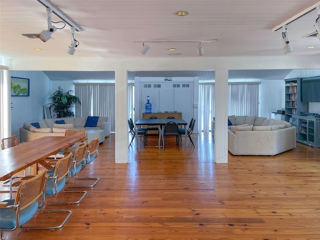 dining space with hardwood / wood-style flooring and rail lighting