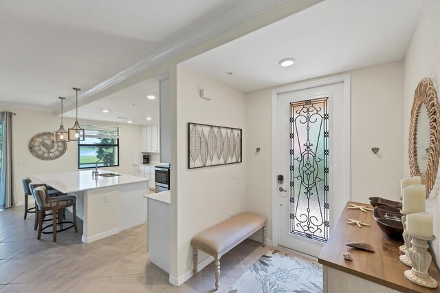 tiled foyer with ornamental molding, an inviting chandelier, and sink