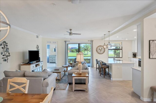 living room featuring crown molding, sink, light tile patterned floors, and ceiling fan