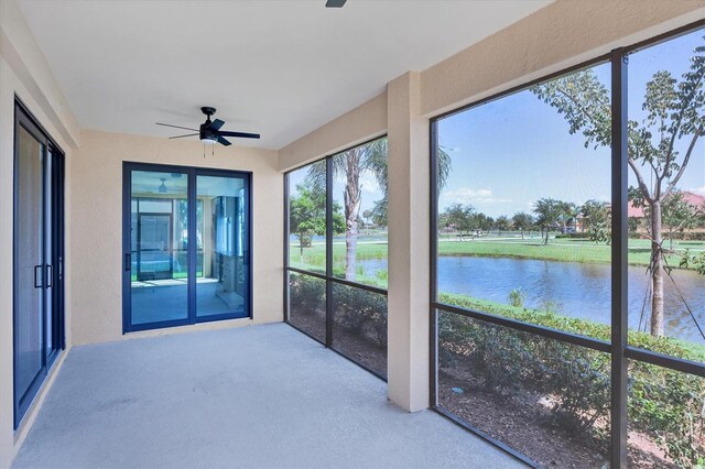 unfurnished sunroom with ceiling fan and a water view