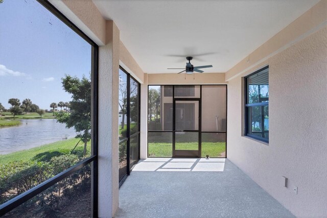 unfurnished sunroom with ceiling fan, a water view, and a wealth of natural light