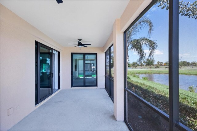 sunroom / solarium featuring ceiling fan and a water view