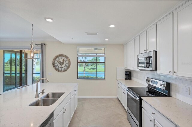 kitchen with pendant lighting, white cabinets, sink, appliances with stainless steel finishes, and light stone countertops