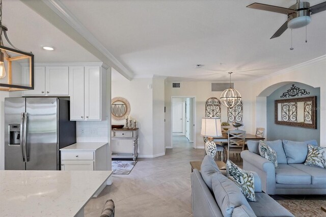 living room with ceiling fan with notable chandelier, ornamental molding, and light tile patterned floors