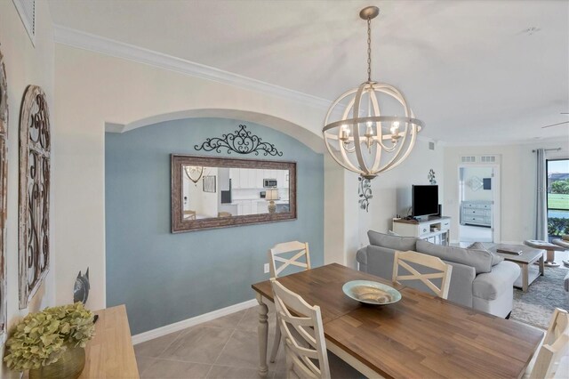 tiled dining space featuring ornamental molding and an inviting chandelier