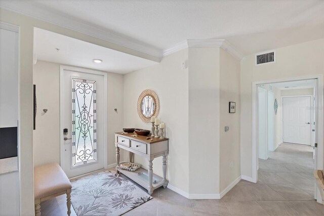 tiled entryway featuring crown molding