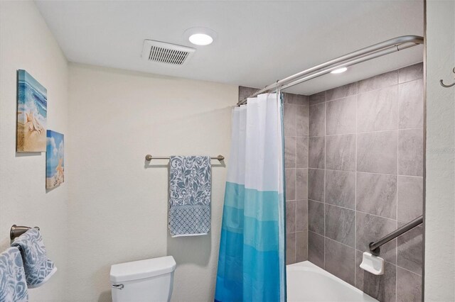 bathroom featuring shower / bath combination with curtain and toilet