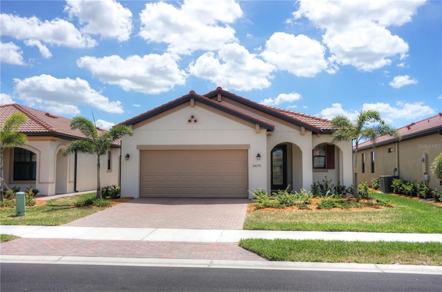 24273 Spartina Dr, Venice, FL 34293 - mediterranean / spanish-style house featuring central AC unit, decorative driveway, a tiled roof, and stucco siding