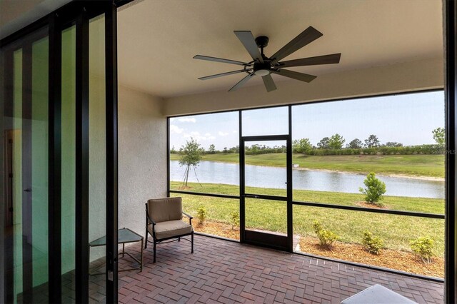 sunroom with a water view and ceiling fan