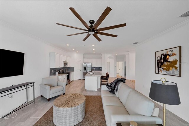 living room featuring ceiling fan, sink, ornamental molding, and light tile patterned flooring