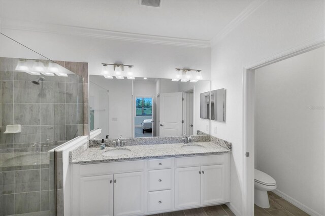 bathroom with a tile shower, vanity, toilet, and crown molding