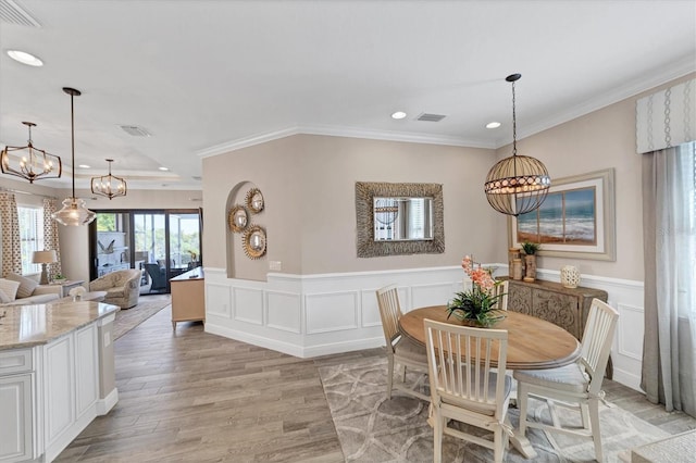 dining area with crown molding, a chandelier, and light wood-type flooring