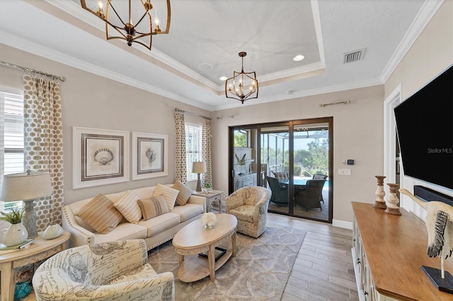 living room featuring a raised ceiling, light wood-type flooring, crown molding, and a chandelier