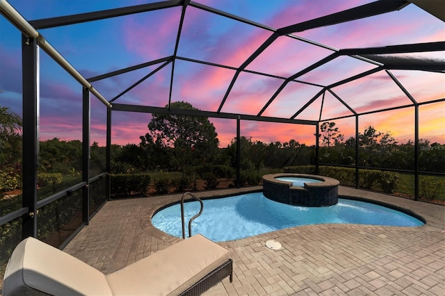 pool at dusk featuring an in ground hot tub, glass enclosure, and a patio area