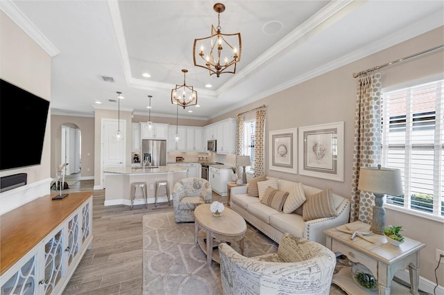 living room with a raised ceiling, crown molding, and light wood-type flooring