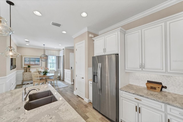 kitchen featuring pendant lighting, white cabinets, sink, stainless steel fridge, and light hardwood / wood-style floors