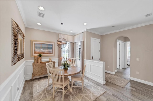 dining space featuring light wood-type flooring, crown molding, and an inviting chandelier