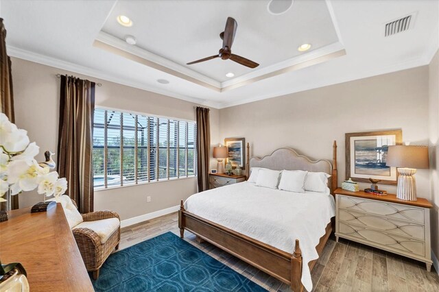 bedroom featuring a raised ceiling, ceiling fan, and hardwood / wood-style floors