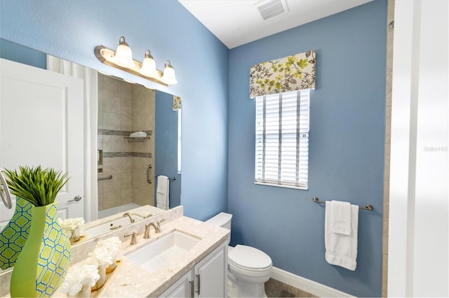 bathroom featuring a tile shower, vanity, and toilet