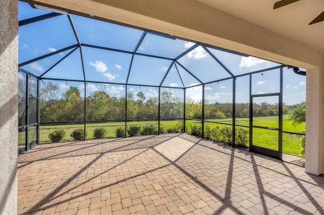 view of patio with ceiling fan and glass enclosure