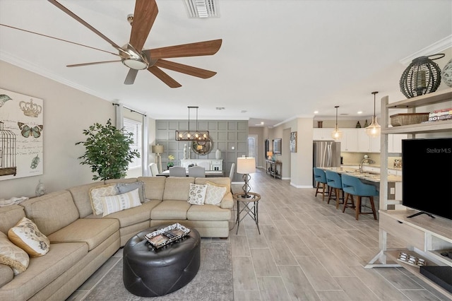 living room featuring ornamental molding, ceiling fan with notable chandelier, and light hardwood / wood-style floors