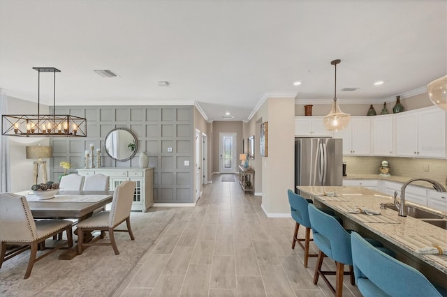 dining area featuring sink, crown molding, and light hardwood / wood-style floors