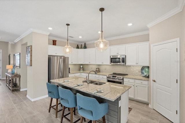 kitchen with white cabinets, hanging light fixtures, an island with sink, appliances with stainless steel finishes, and sink