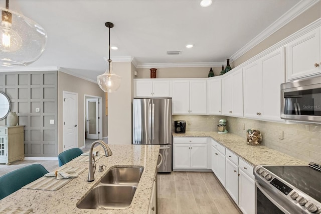 kitchen featuring light hardwood / wood-style flooring, sink, pendant lighting, white cabinetry, and appliances with stainless steel finishes