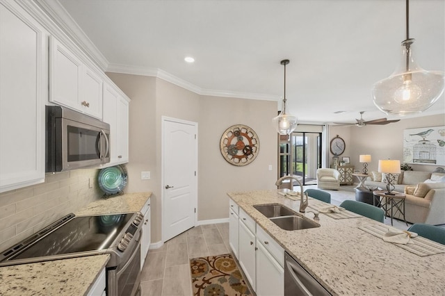 kitchen with decorative backsplash, hanging light fixtures, white cabinetry, sink, and stainless steel appliances