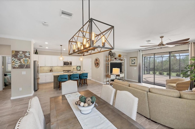 dining area with crown molding, sink, ceiling fan with notable chandelier, and light wood-type flooring