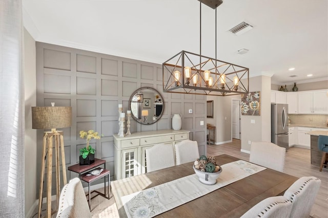 dining area with ornamental molding, light hardwood / wood-style flooring, and a chandelier