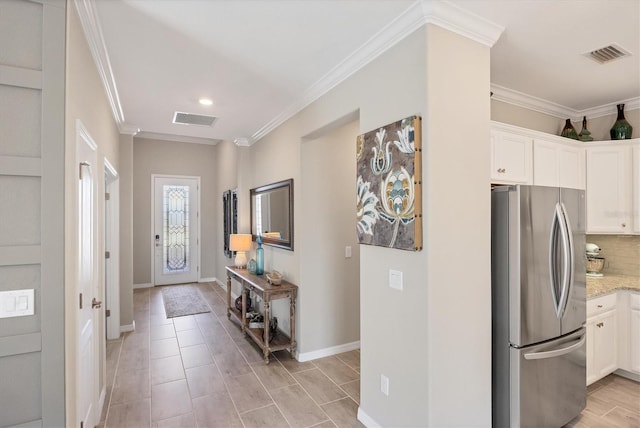 kitchen featuring white cabinetry, crown molding, light stone countertops, and stainless steel fridge