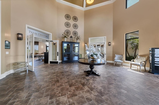 foyer with french doors, crown molding, and a towering ceiling