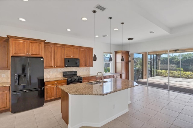 kitchen with light stone counters, sink, black appliances, light tile patterned floors, and decorative light fixtures