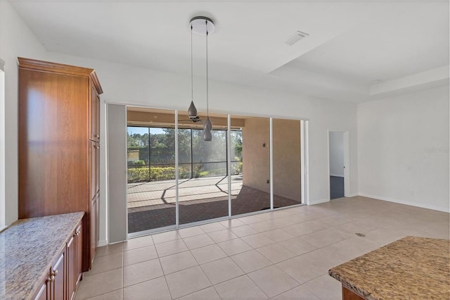 interior space with a raised ceiling and light tile patterned floors