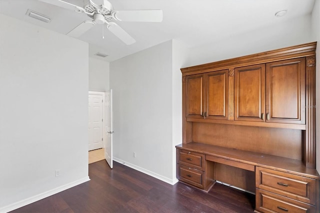 unfurnished office featuring ceiling fan, dark hardwood / wood-style flooring, and built in desk