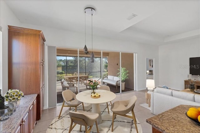 dining space featuring light tile patterned floors and a tray ceiling