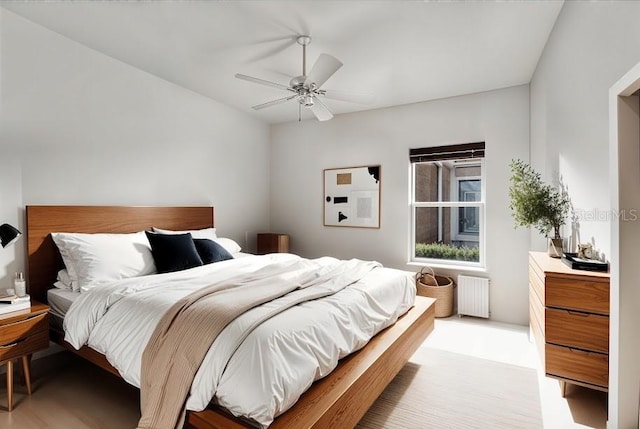 bedroom with ceiling fan, radiator heating unit, and light hardwood / wood-style floors